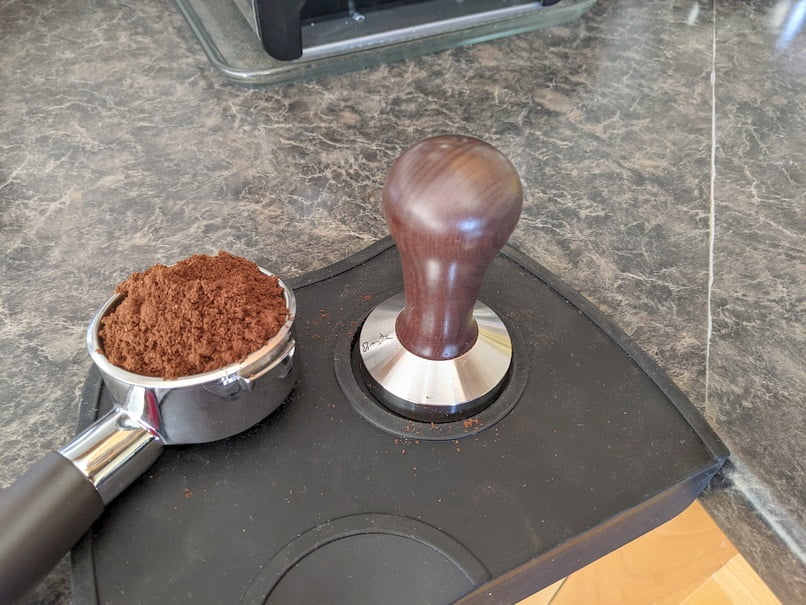 Tamper and ground coffee in portafilter.