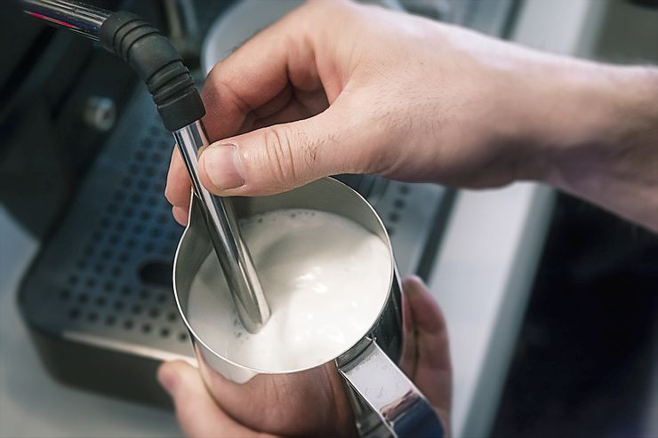 barista steaming milk in coffee shop