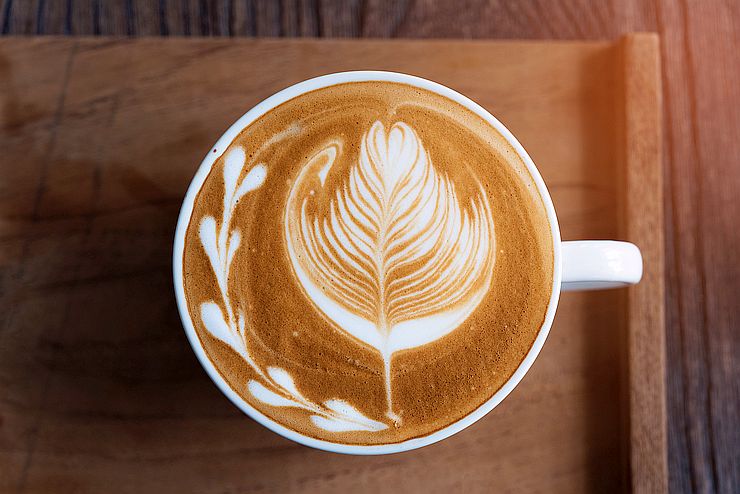 intricate latte art on wooden tray