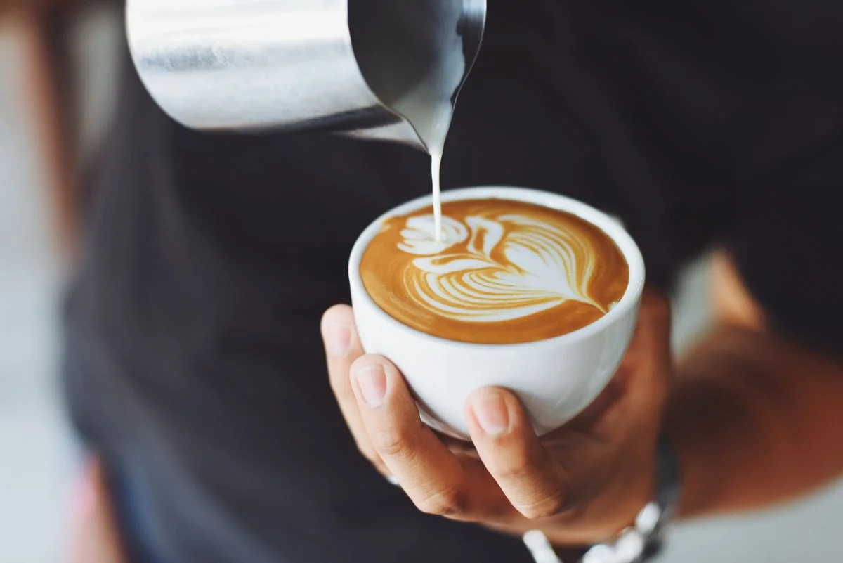 barista creating latte art with steamed milk