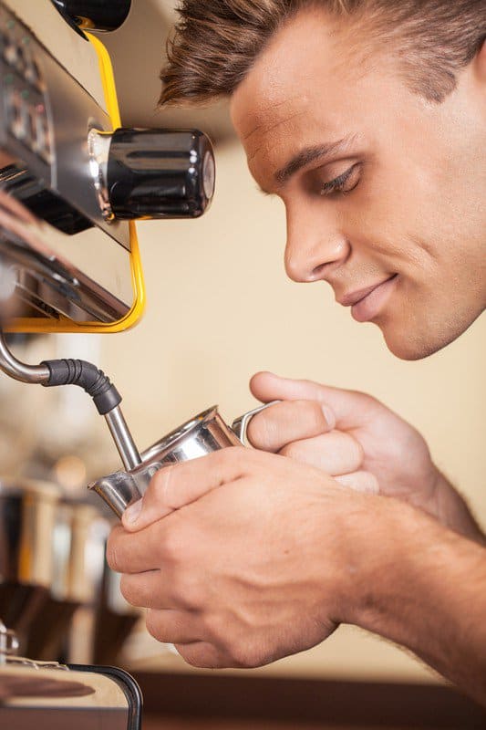 barista steaming milk with the wand 