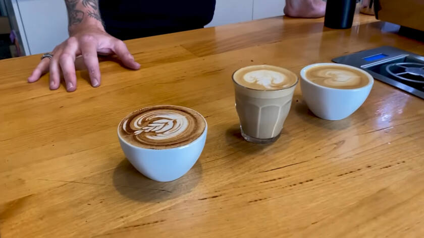 Three latte art designs on wooden table. latte cappuccino and flat white