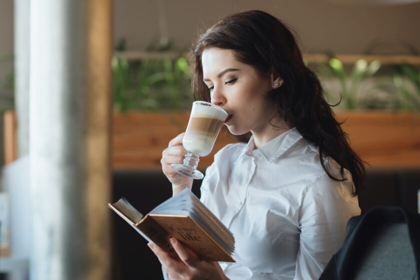 Woman sipping coffee while reading a book.