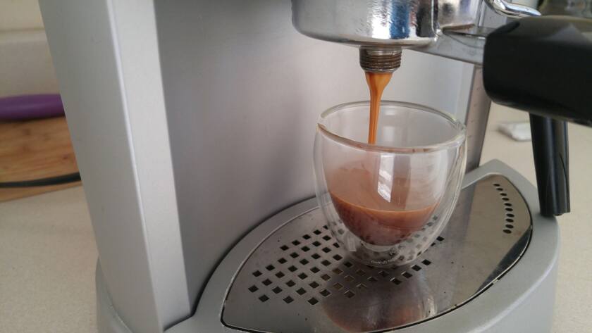 Espresso pouring into glass from coffee machine.